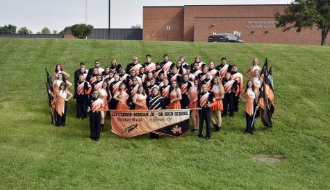 All band members from instument players to flag holders pose with one another for a picture. 